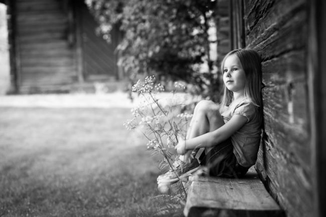 Girl sitting against timber wall