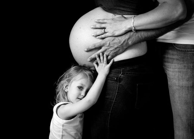 Girl holding her hands on mums belly